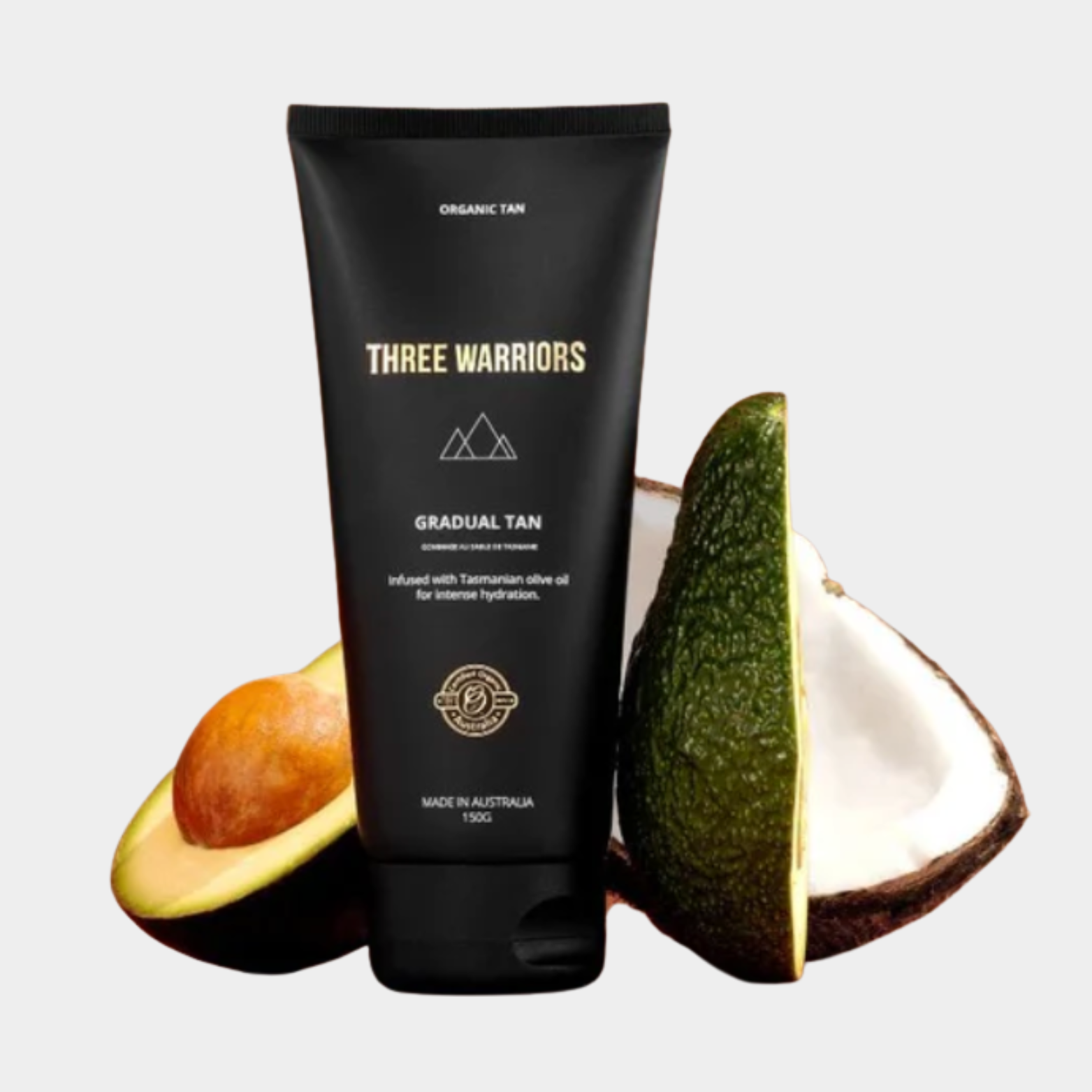 Three Warriors gradual tan product with avocado and coconut on a light gray background